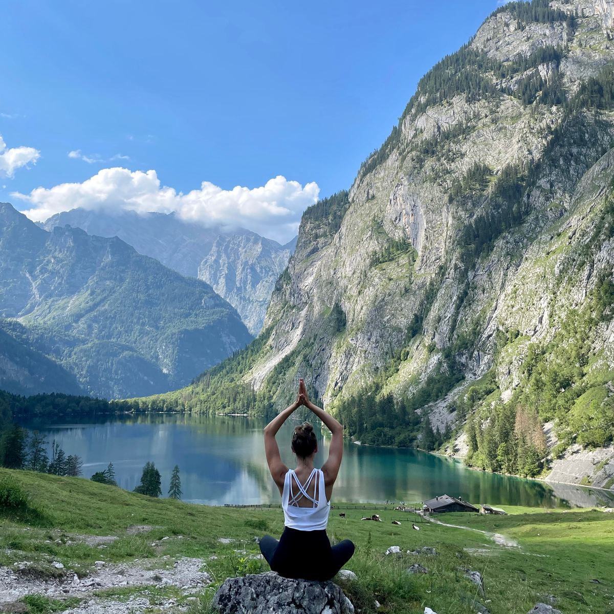 Meditative Sitzhaltung mit Blick auf einen Bergsee, Moment der Klarheit und Reflexion